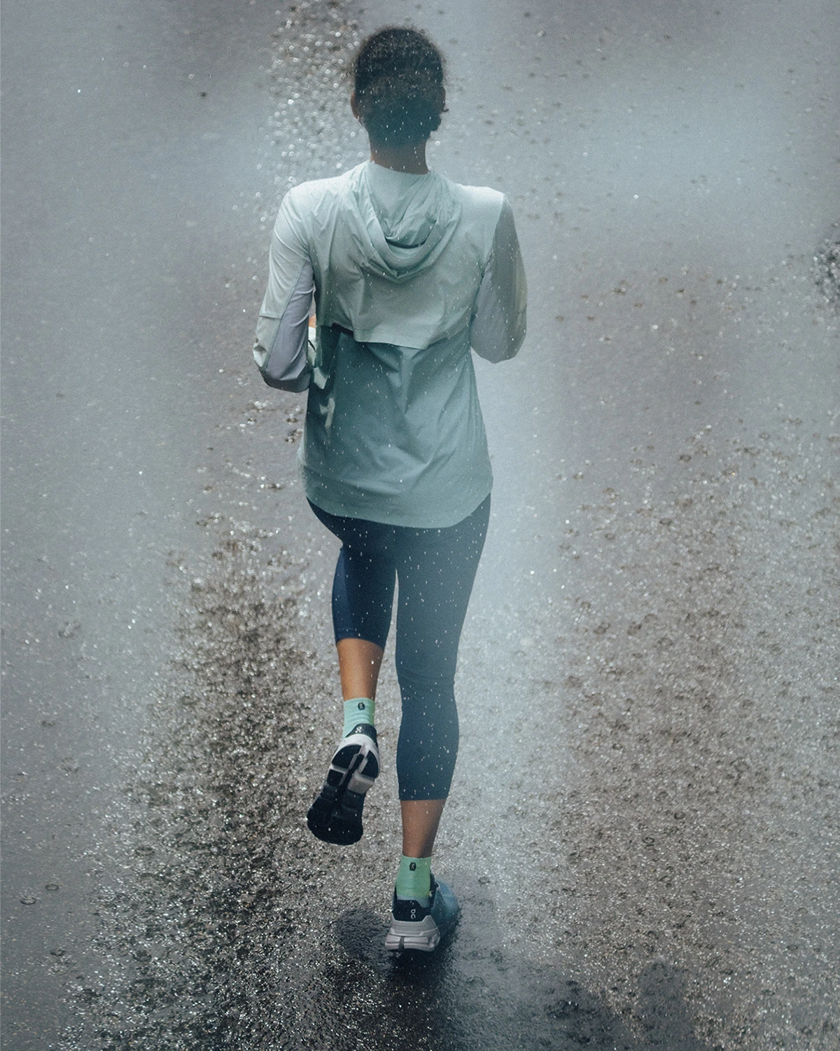 Close-up of woman running down the road in the Weather Jacket and Active Tights, shot from behind.