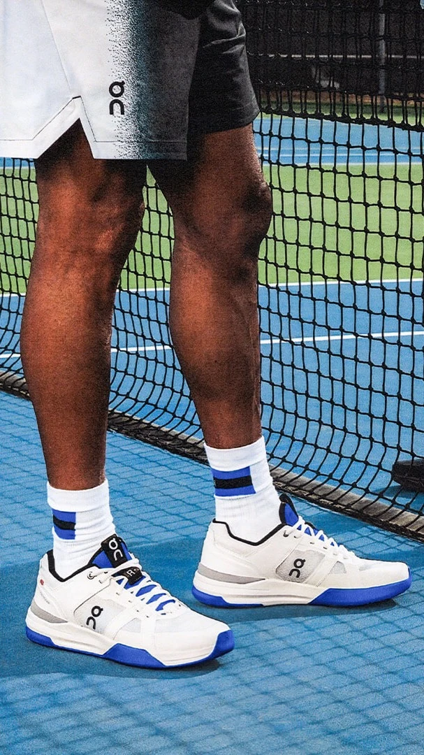 Two tennis players wearing On tennis shoes meet at the net.