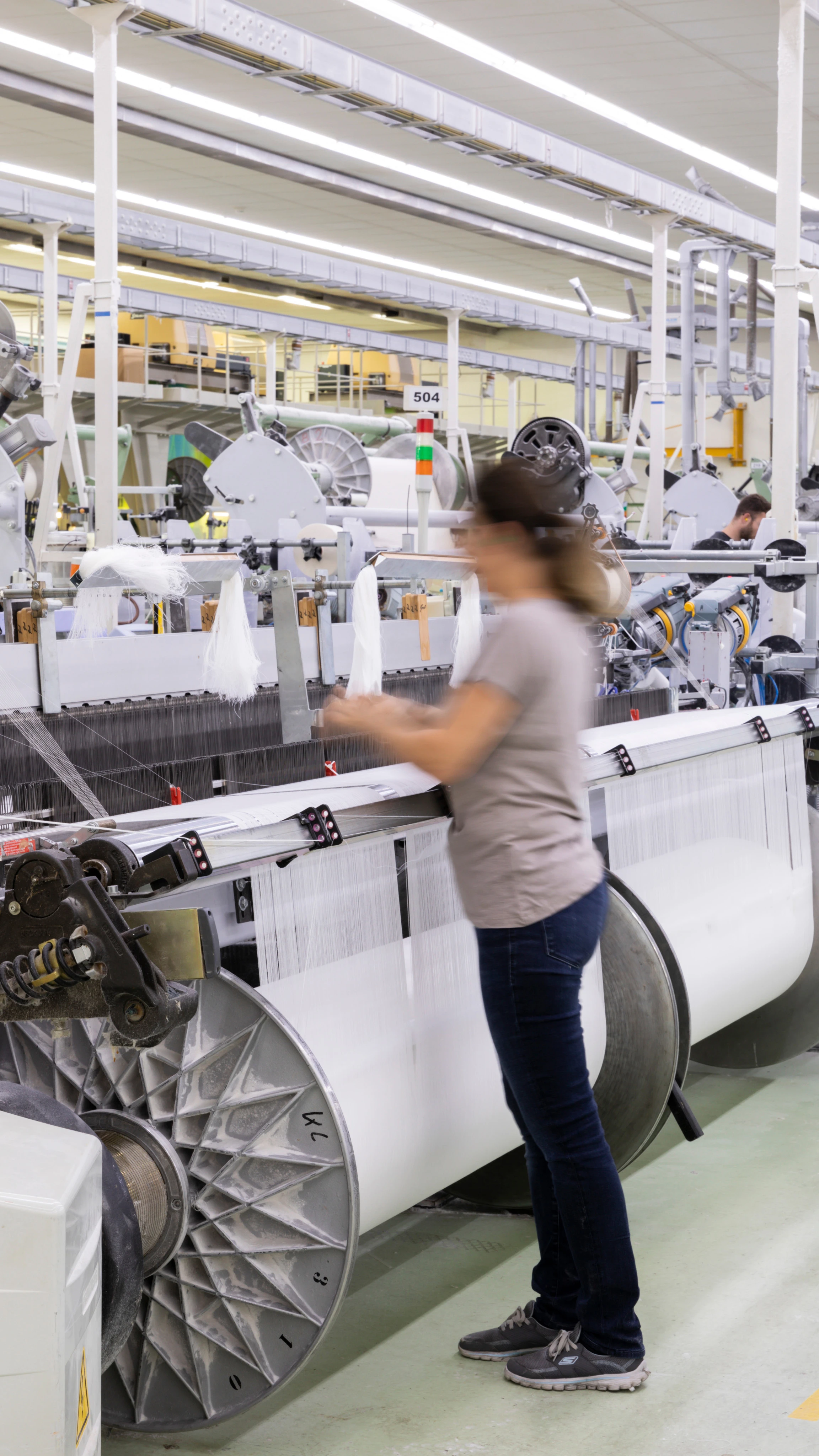 A wide shot of a woman working at one of our factories.