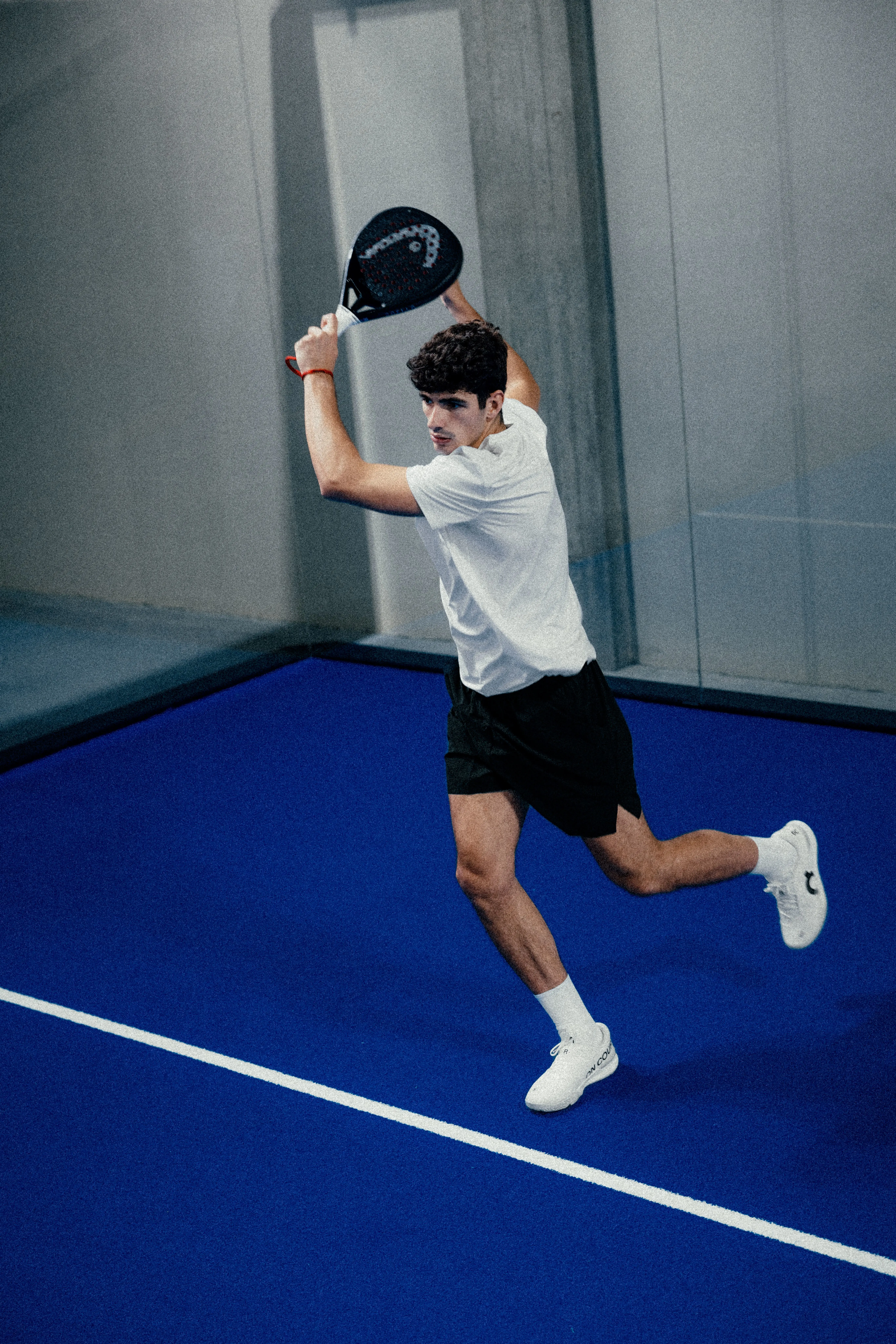 A padel player in On gear, readying to serve.