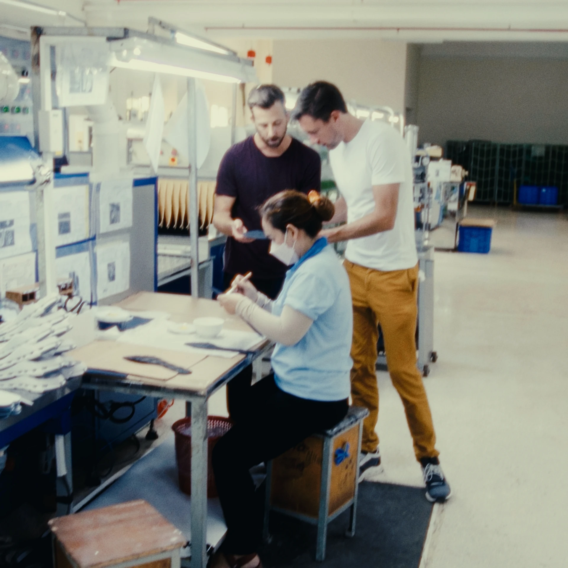 Three people, one seated woman and two standing men, working hard in the On Lab.