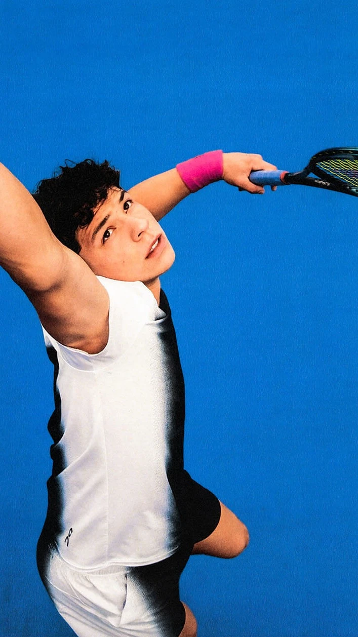 Ben Shelton throws a tennis ball into the air as he prepares to serve.
