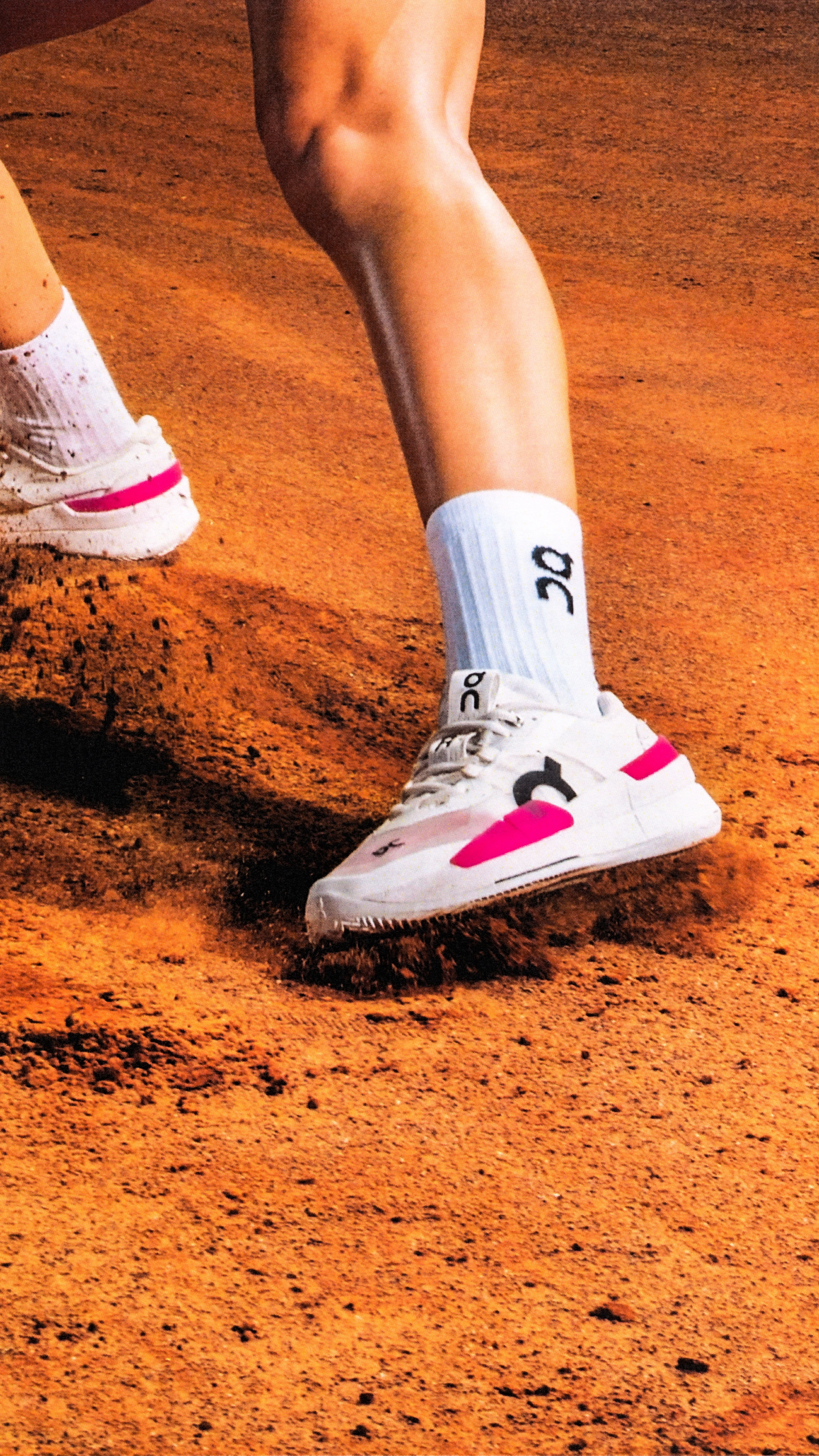A tennis player slides on the clay court, causing their shoes to need to be washed later.
