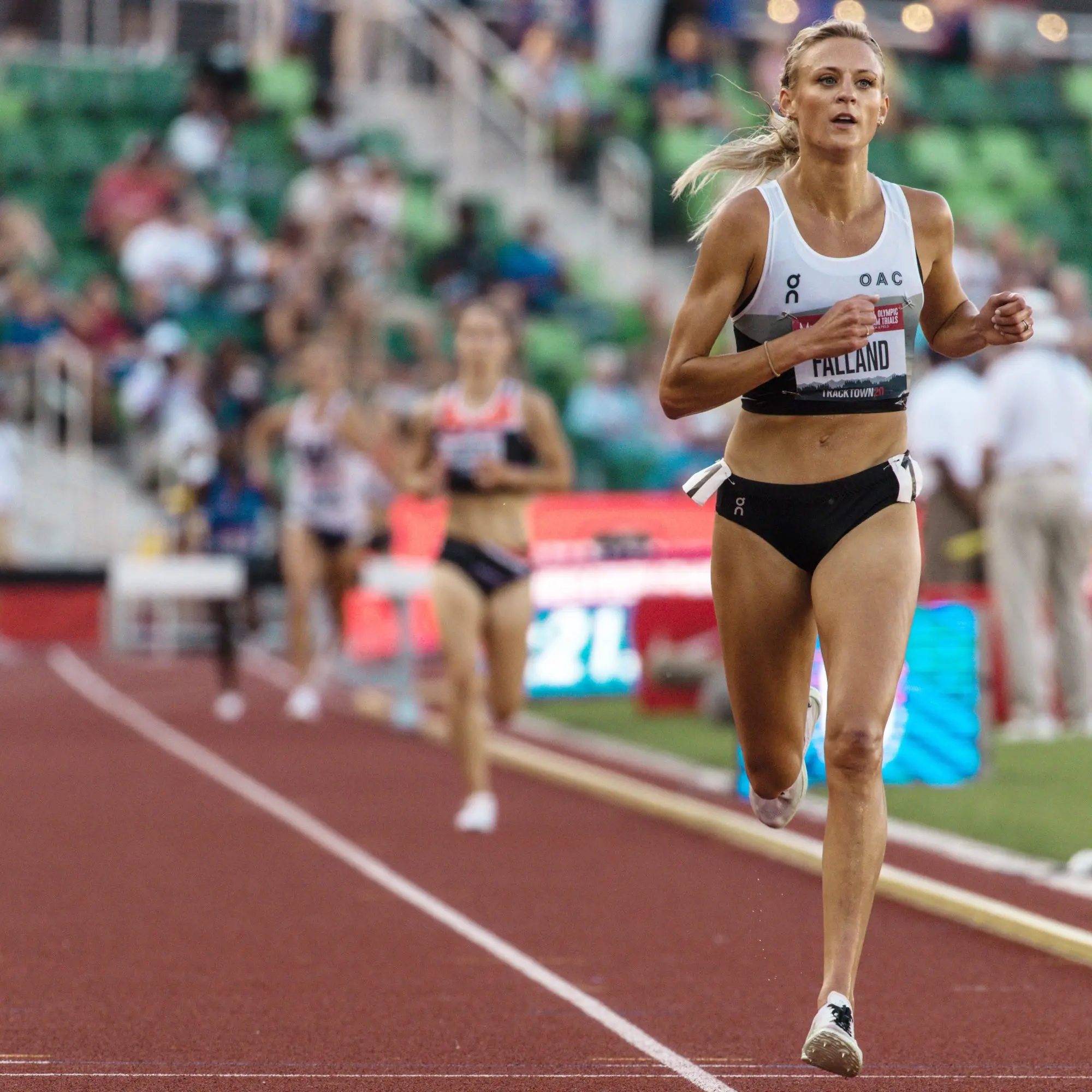 Leah Falland running on track in On gear, as other runners are trailing behind her.