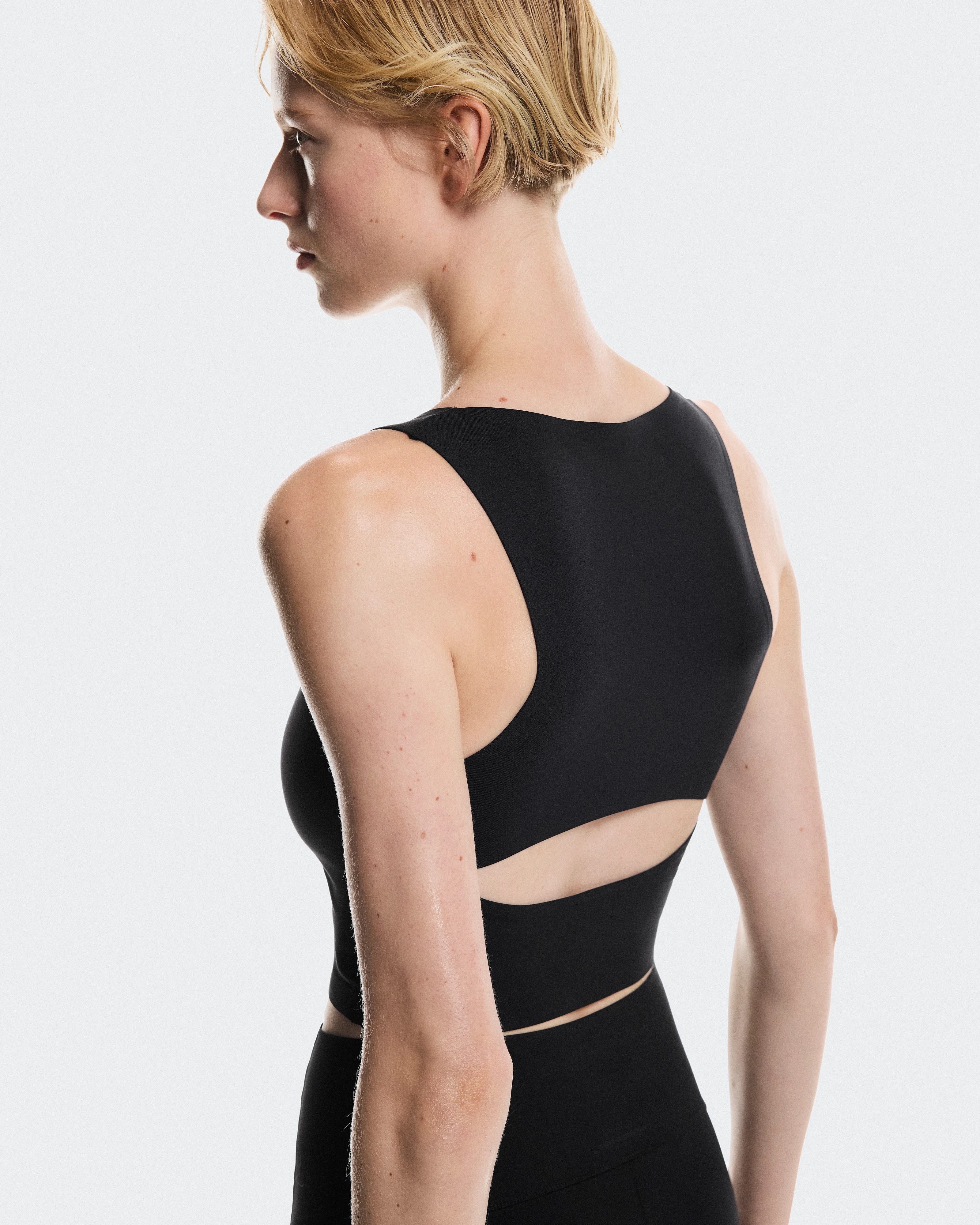 Side profile of a female athlete wearing black On performance gear and looking into the distance.