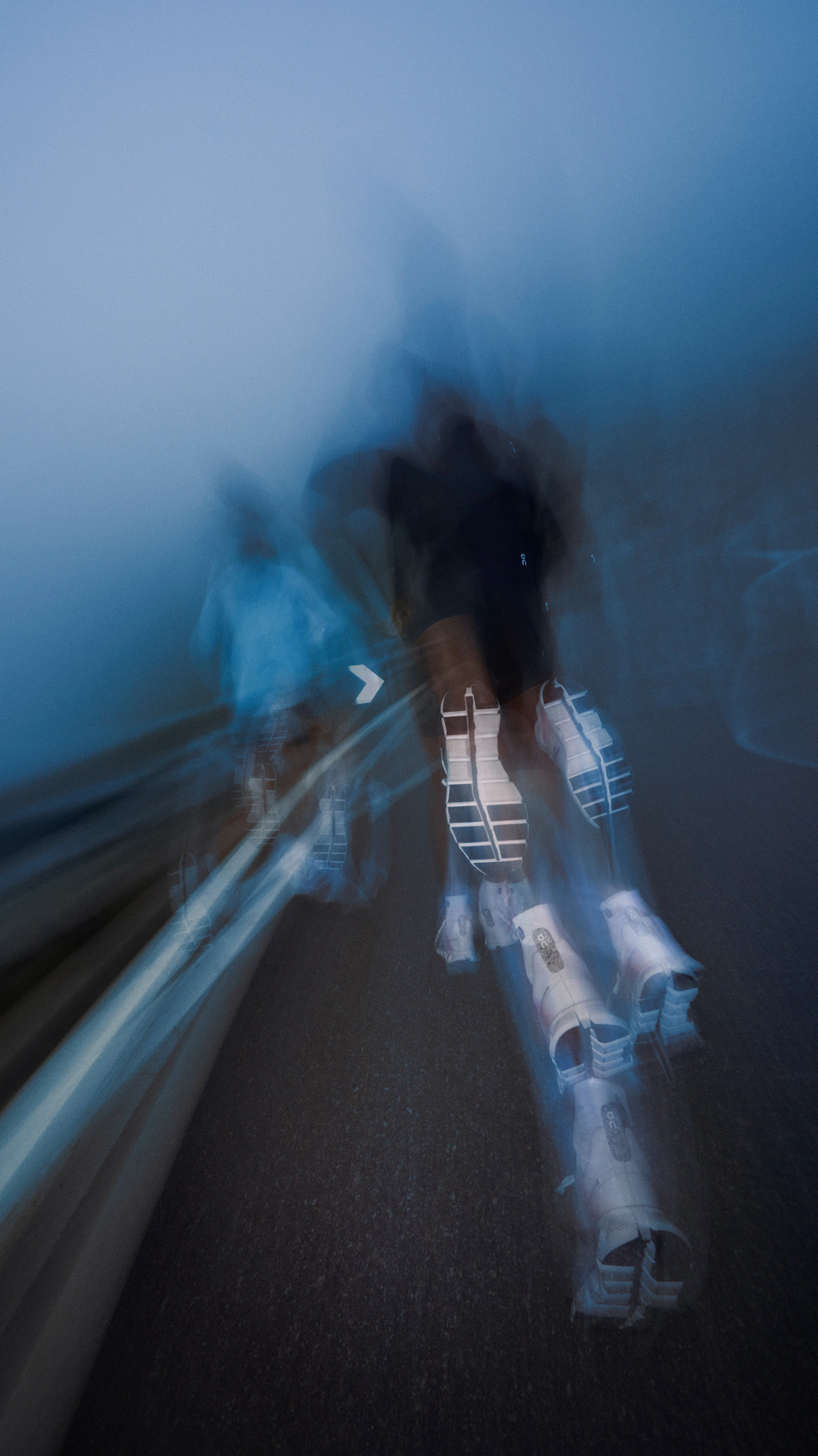 Two people running through the streets on wet asphalt. A blurry light effect suggests they are moving quickly.