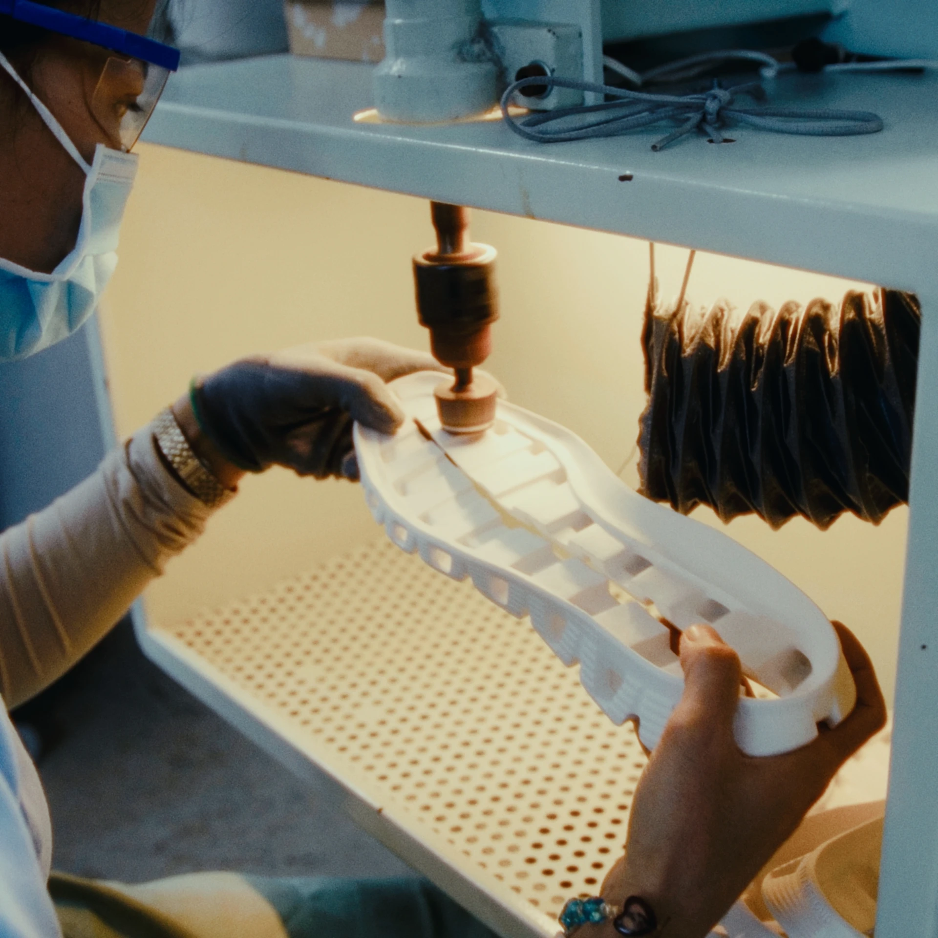 Lab technician working with a machine on the Cloudprime outsole, while wearing glasses and a mask.