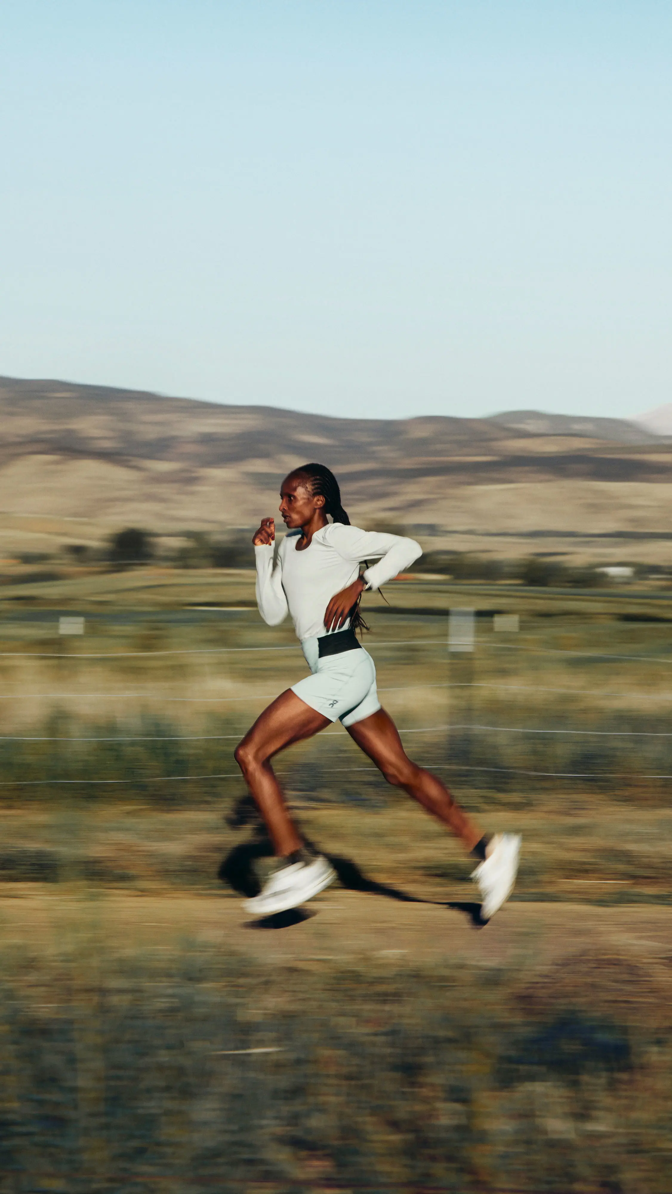Hellen Obiri running in a mountain landscape.