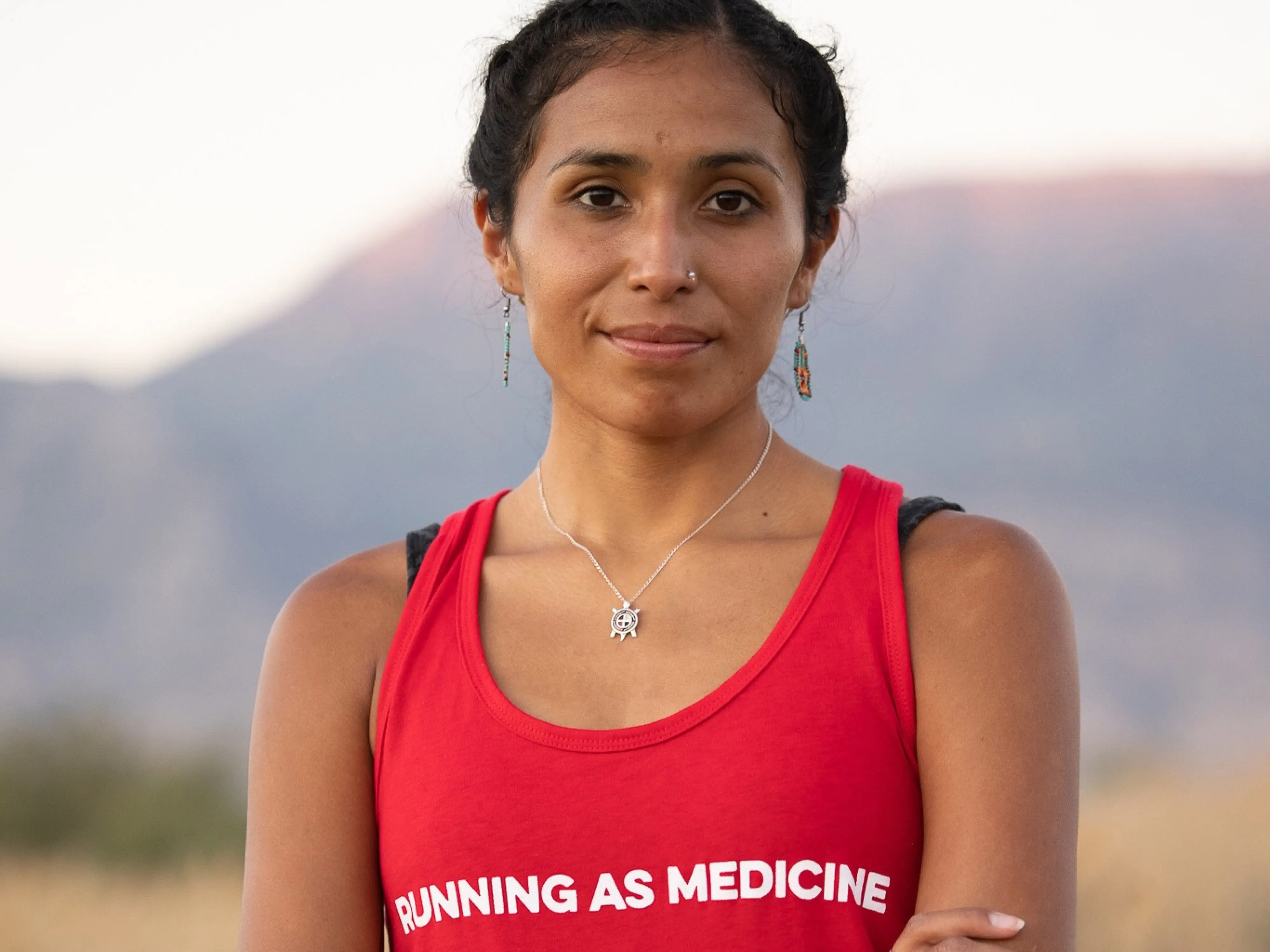 indigenous women facing camera wearing a shirt reading, running as medicine