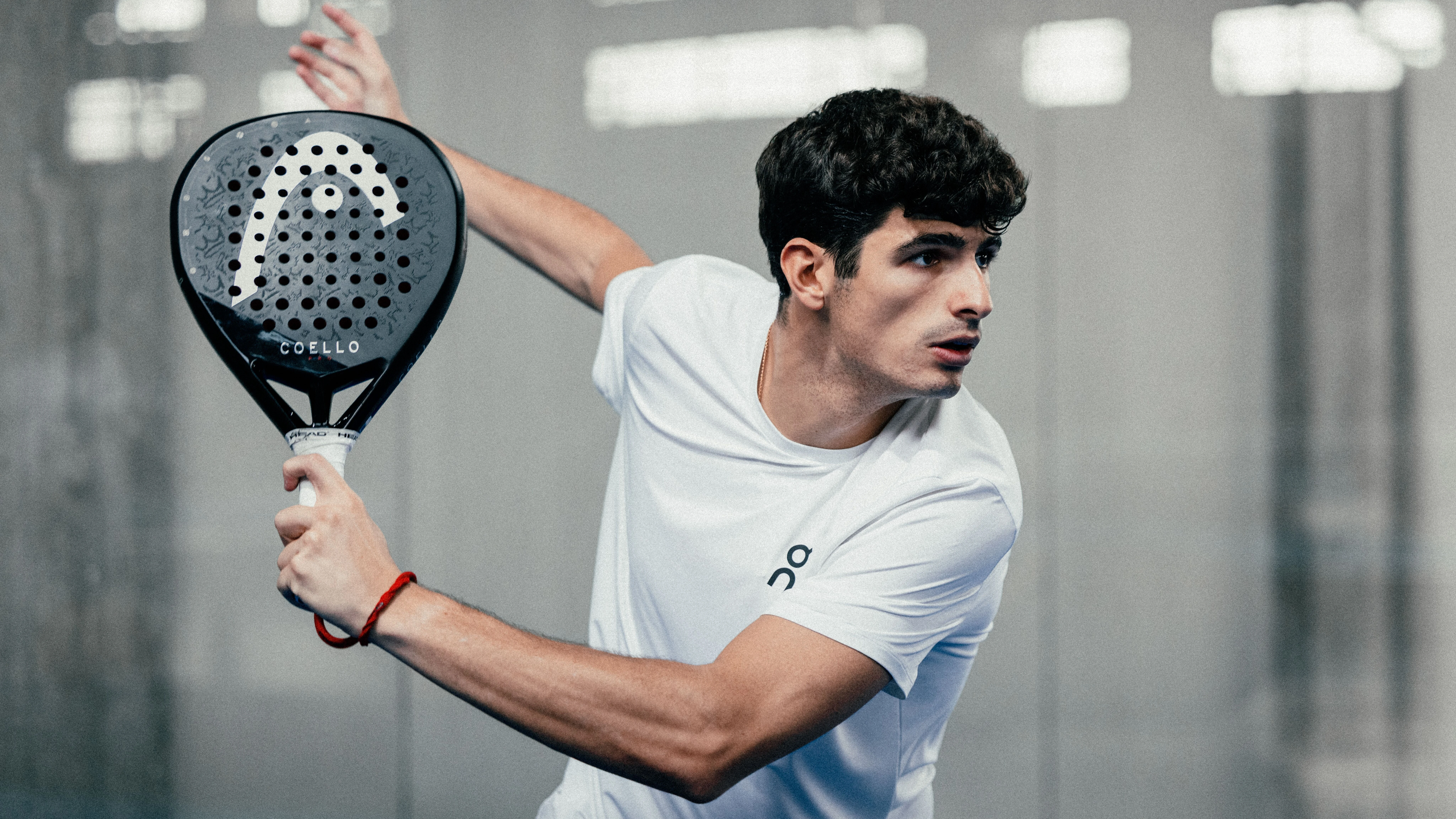 A padel player in On gear in the ready position, padel up.