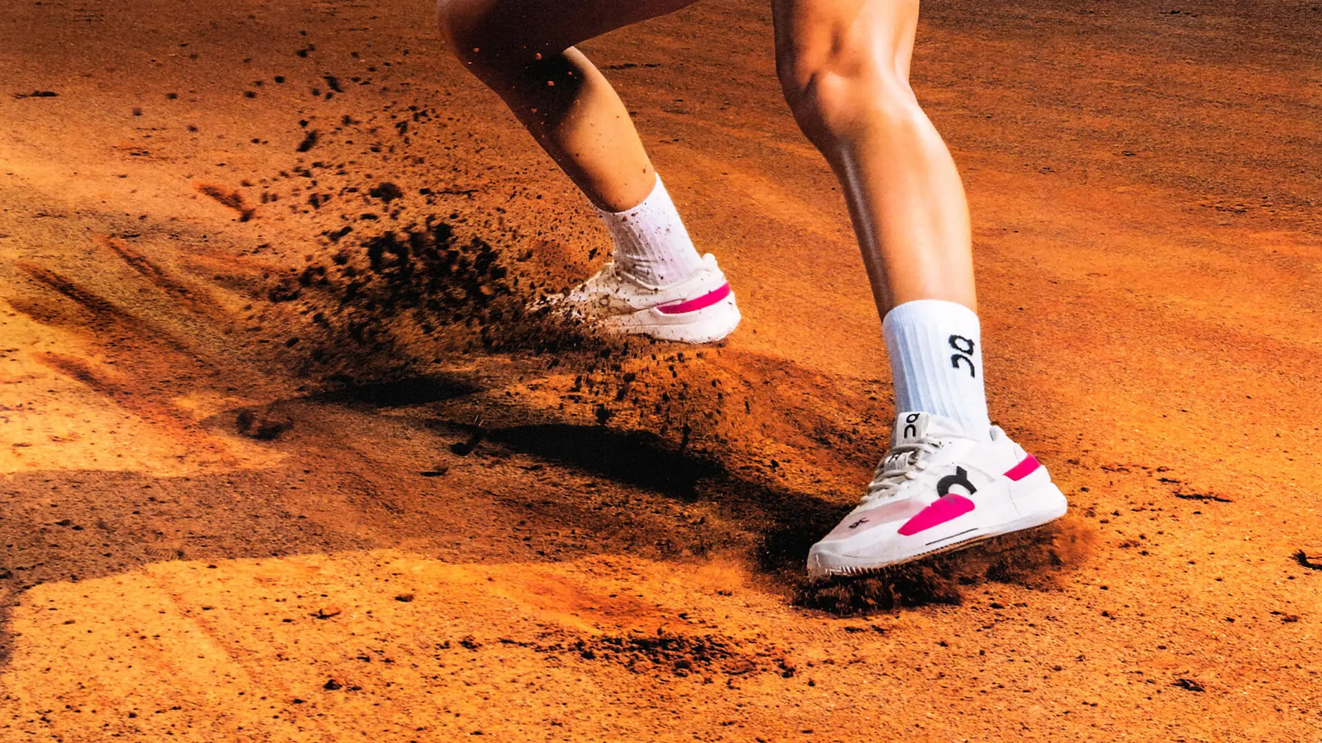 A person wearing THE ROGER Pro 2 Clay tennis shoes slides across the court.