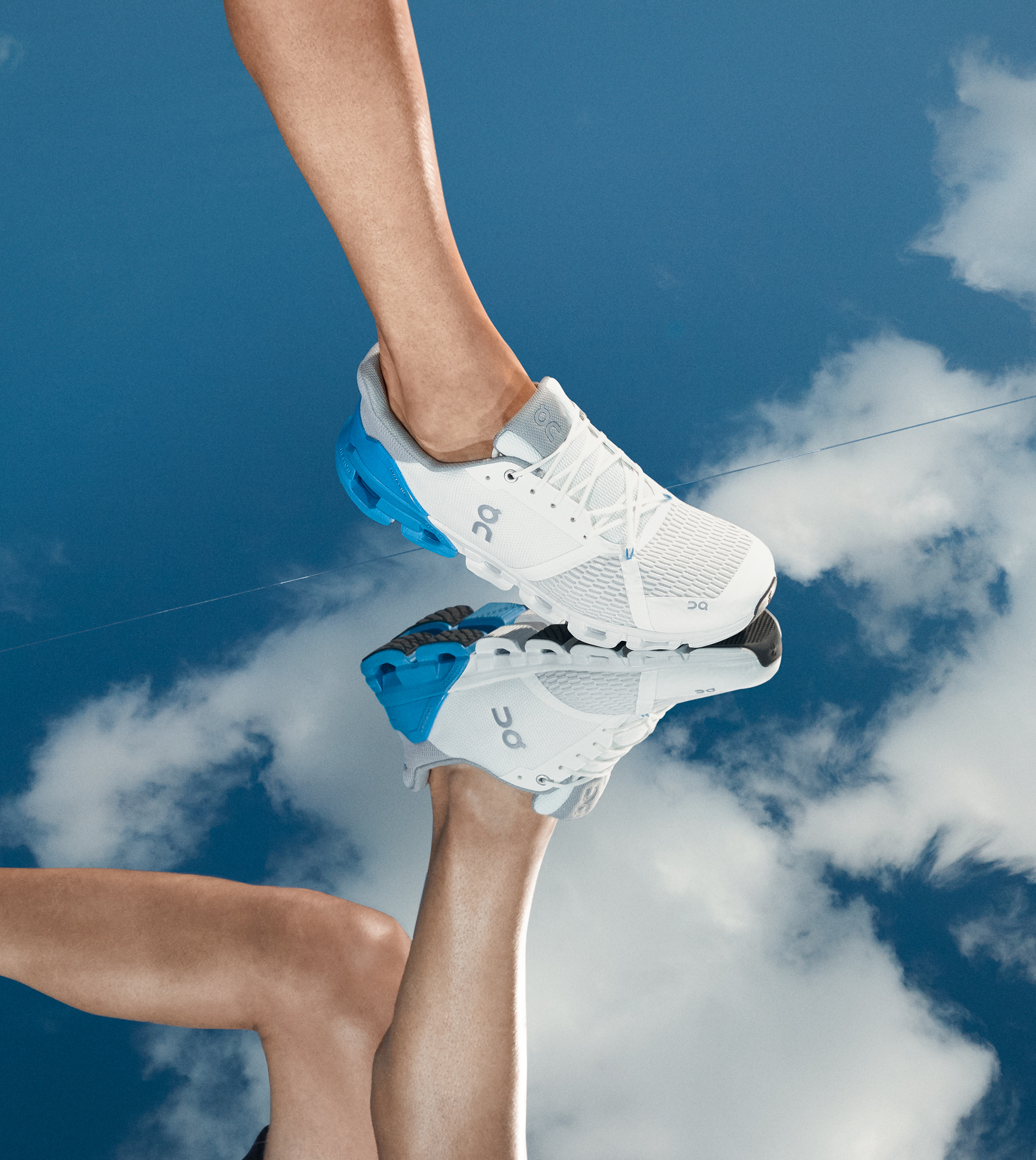Person wearing blue and white Cloudflyer stepping onto a mirrored surface with clouds.