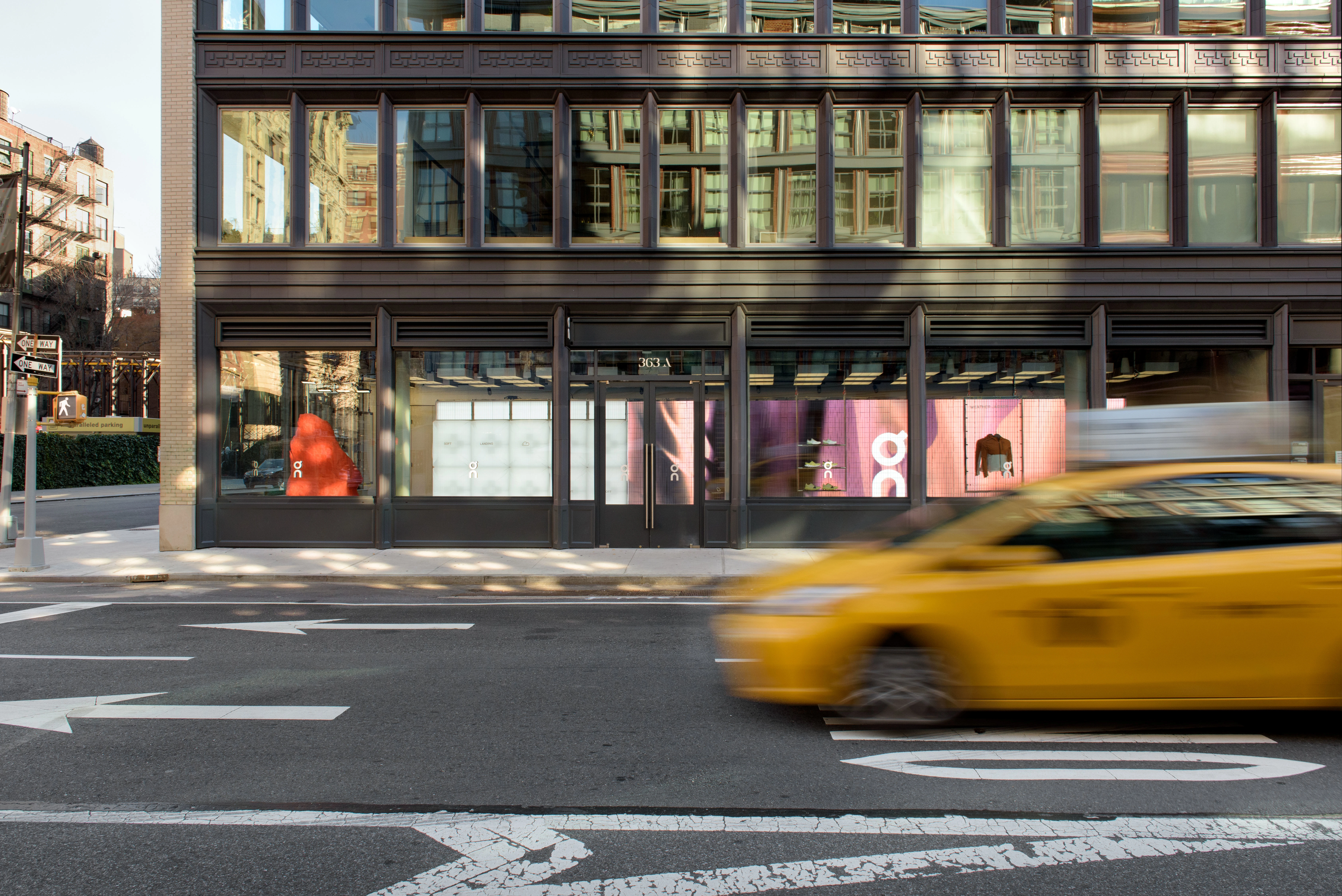 Outdoor shot of On store in NYC, with a blurred yellow taxi in the foreground.