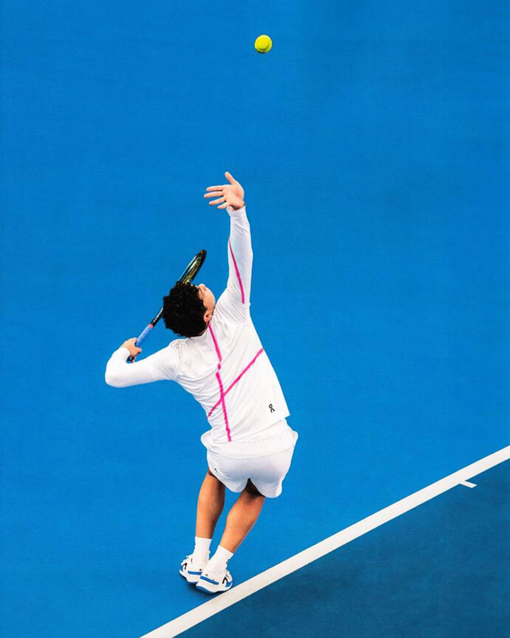 Ben Shelton prepares to serve by tossing the tennis ball high into the air.