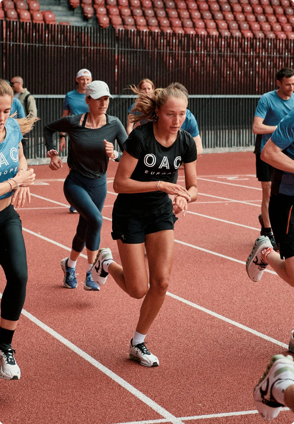 Woman in OAC shirt running among other athletes on an orange track.