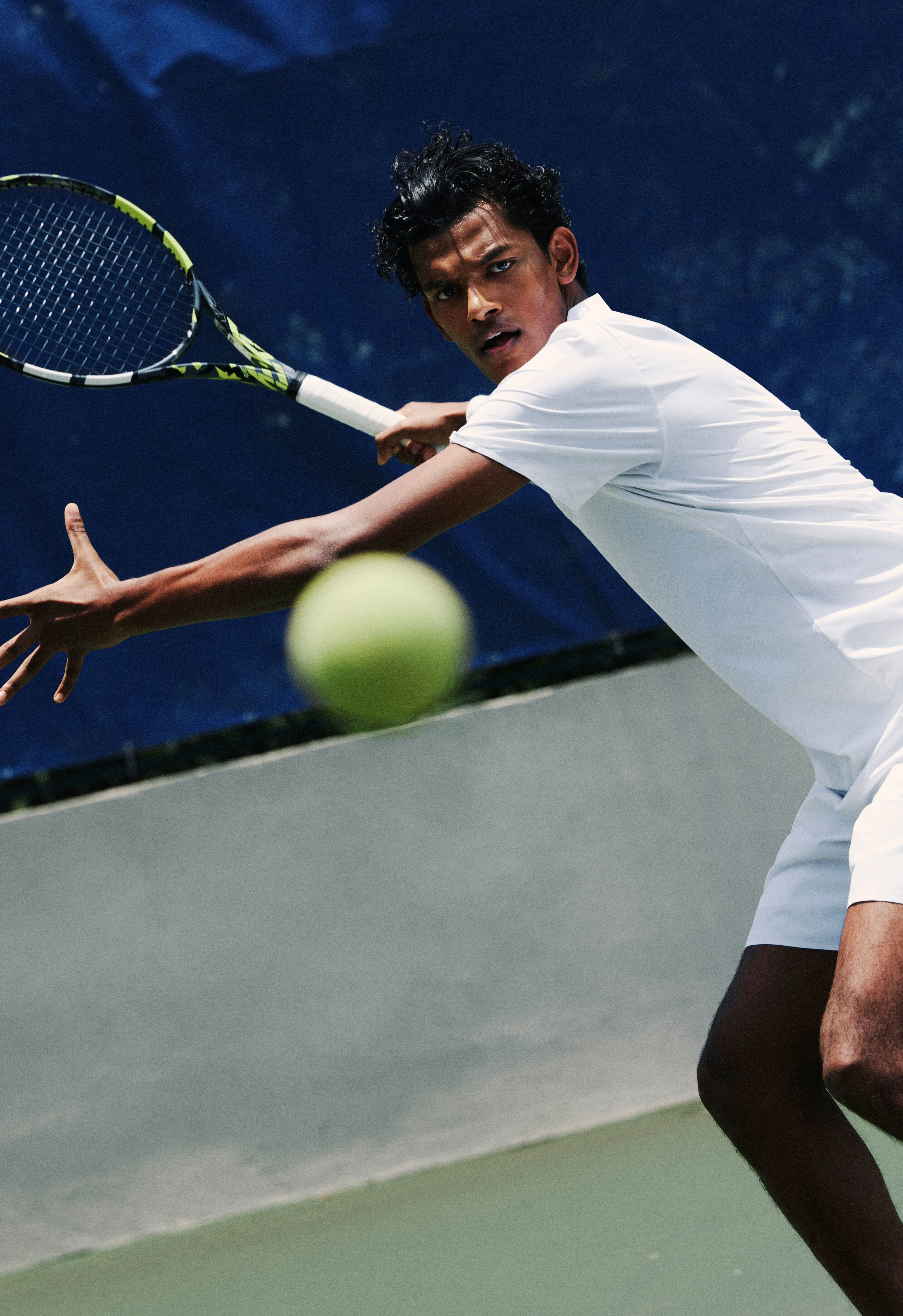 A tennis player ready to hit the ball, with the ball in the foreground.