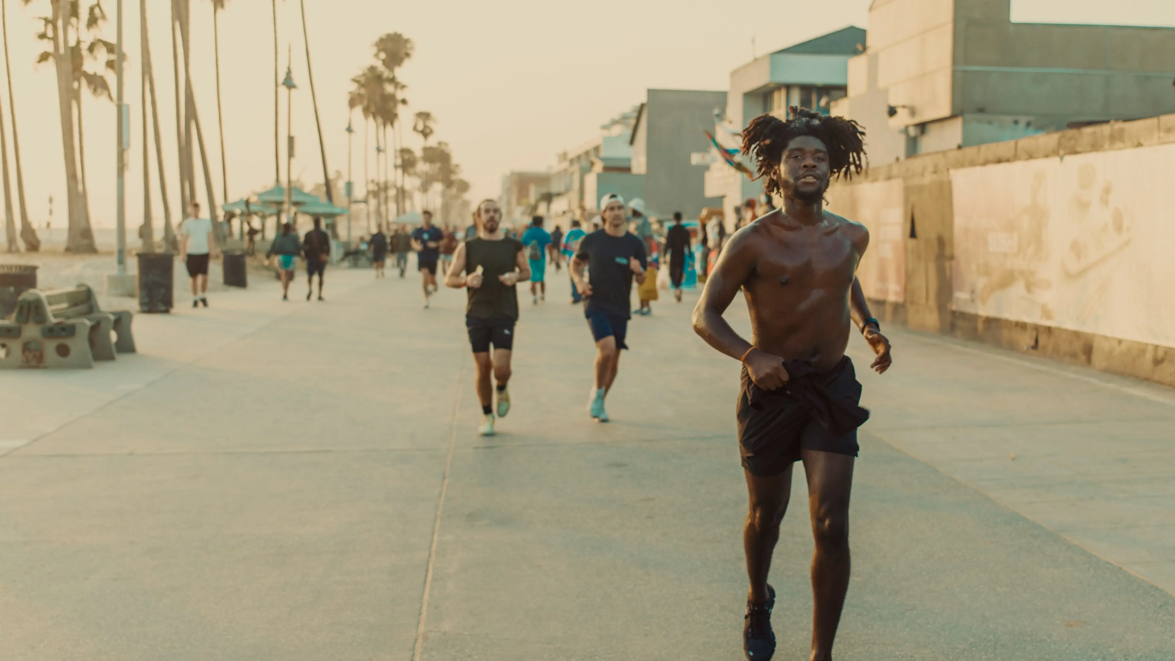 man running shirtless alongside beach front